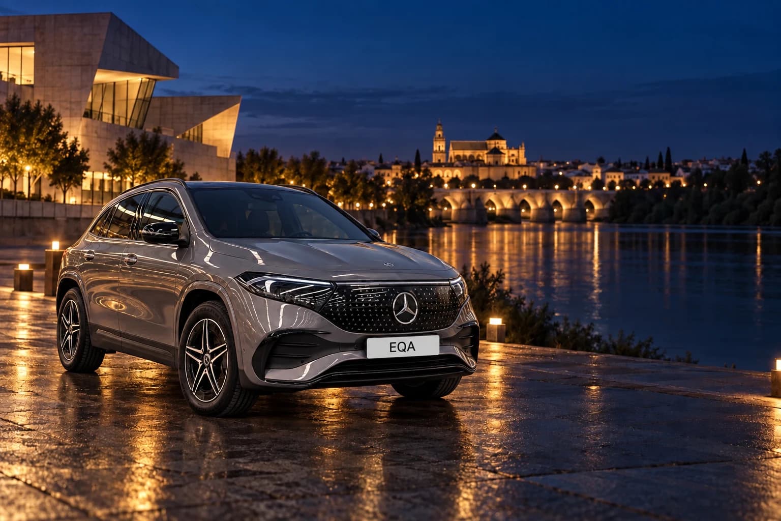 Mercedes-Benz EQA gris a orillas del Guadalquivir en Córdoba al anochecer, con el Puente Romano iluminado