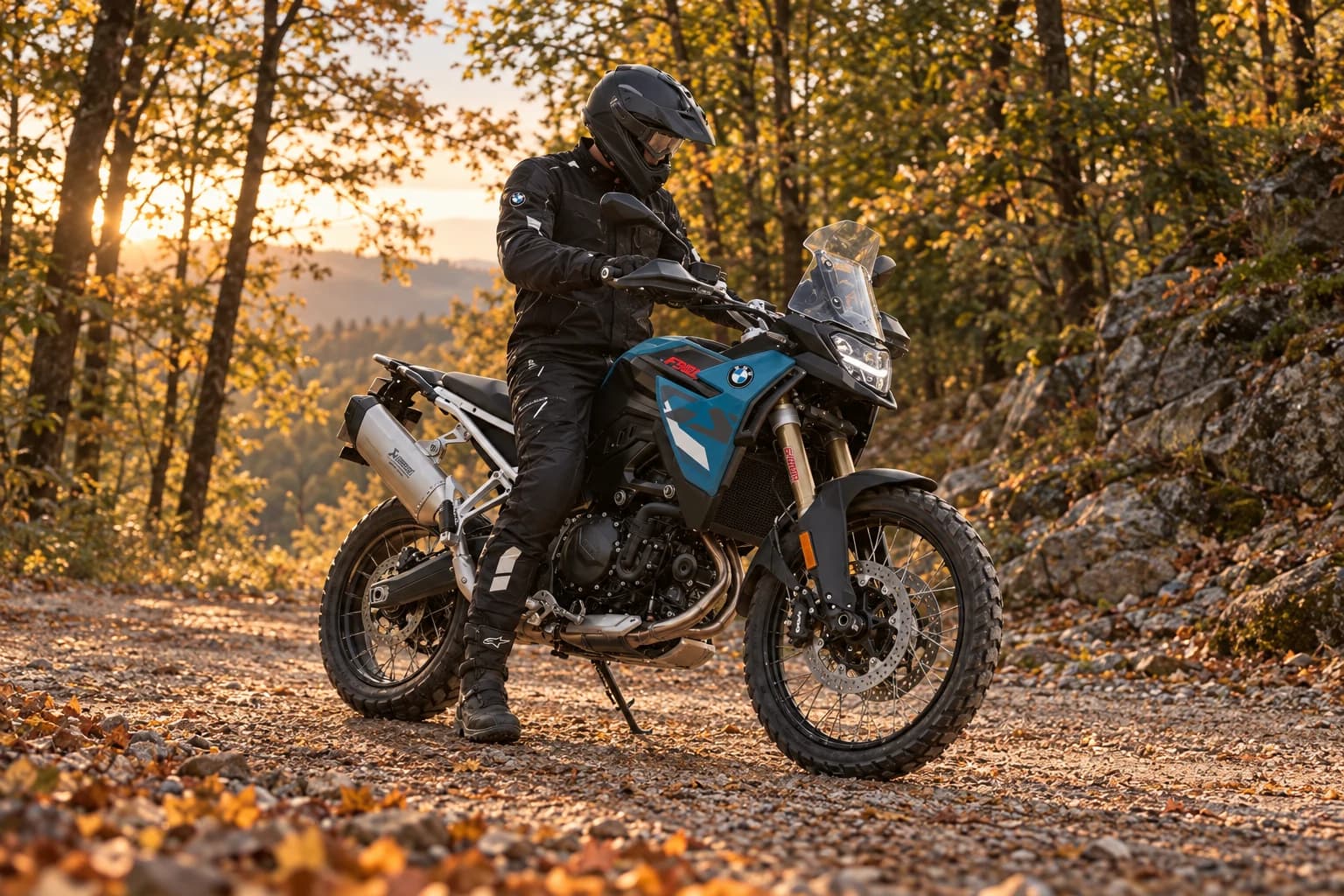 BMW F 900 GS parada en una pista de grava en un bosque otoñal