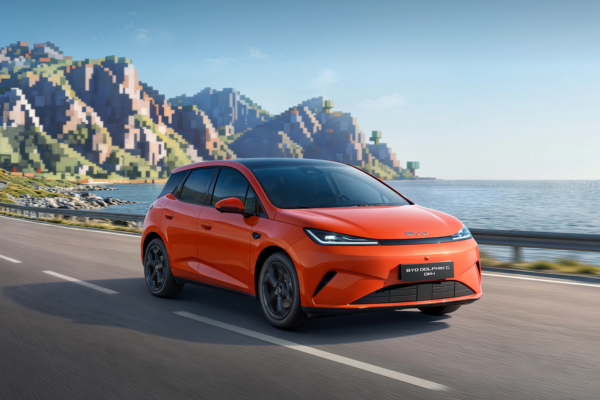 BYD Dolphin G DM-i naranja en carretera costera con montañas de fondo