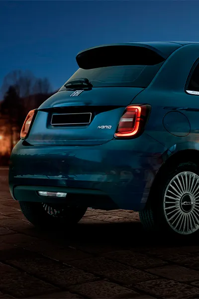 Foto trasera del Fiat 500 azul de noche con luces encendidas