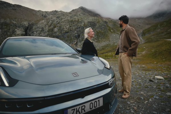 Dos personas junto a un coche Zeekr 001 en azul en un paisaje de montaña